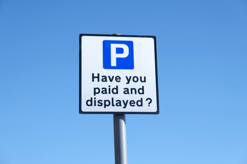 Paid and displayed car park sign against blue sky